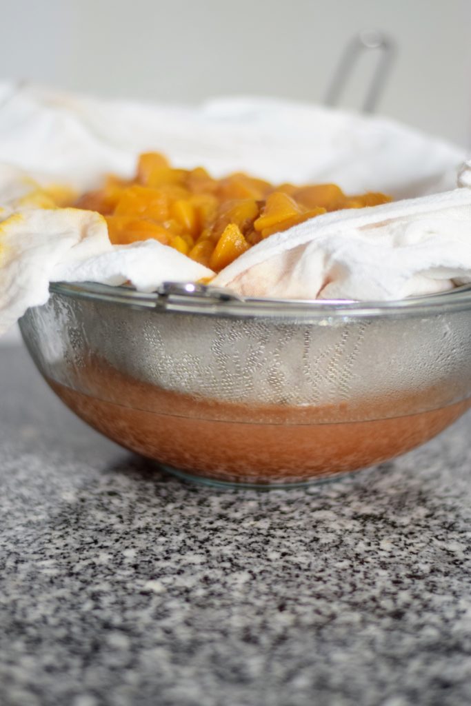 straining cooked peaches for canned peach syrup at Spirit's Freedom Farm