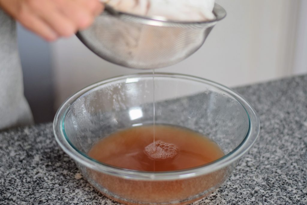 straining yummy syrup from cooked peaches for canned peach syrup at Spirit's Freedom Farm